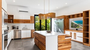 A modern kitchen with a central island, built-in appliances, and a large window with a view. - Spacious 7BDR Villa with Private Pool, Outdoor Cinema Nights & Fire Pit + Beach Club Access (Hacienda Pinilla)