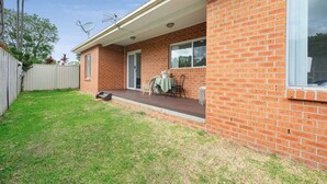 Une maison de plain-pied en briques, dotée d’un porche abrité, d’une petite pelouse et d’une clôture en bois.
