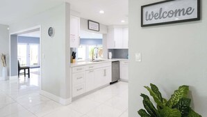 A modern kitchen with white cabinets, a sink, and a welcome sign. - Private Pool 4BR · 6 Min to Fort Lauderdale Beach (Fort Lauderdale)