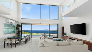 Ein großzügiger Wohnbereich mit einem großen Glasfenster, das auf einen Balkon mit Meerblick führt.
