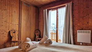 A wooden room with a bed, a chair, a small table, and a window with curtains. - La Tanière by Interhome (Nendaz)
