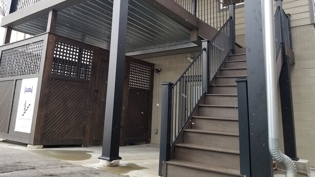 Un immeuble de deux étages doté d’un balcon, d’un escalier et d’une entrée fermée par un portail.