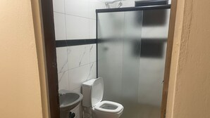 Un baño pequeño con inodoro, lavamanos y un cubo de basura.