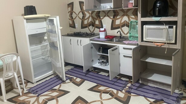 Una cocina compacta equipada con refrigerador, microondas, lavamanos y gabinetes.