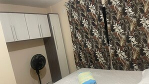 Un dormitorio con cama, ventilador y armario.