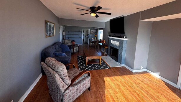 A living room with a sofa, armchair, wooden coffee table, and a fireplace. - Withrow Retreat (Waterville)