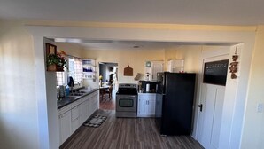A kitchen with white cabinets, a black refrigerator, and a wooden floor. - Withrow Retreat (Waterville)