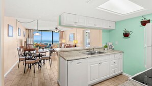 A modern kitchen with white cabinets, a large island with a sink, and a view to the outside. - Beautiful Condo with Panoramic Ocean Views: Double‑Wide Balcony, Heated Pool & Hot Tub ☀️ (Cape Canaveral)