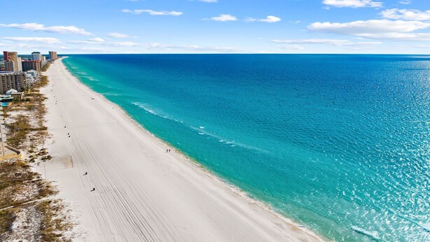 A beach with a clear blue ocean, sandy shore, and buildings along the coastline. - Gulf Views - Private Pool - 4 Bedroom (Panama City)
