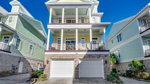 A multi-story residential building with a central balcony, two garages, and a brick facade. - Landyn Beach House (Myrtle Beach)