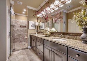 A modern bathroom with a glass shower enclosure, granite countertops, and decorative vases. - Landyn Beach House (Myrtle Beach)