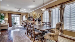 A dining area with a wooden table, chairs, and a chandelier. - Landyn Beach House (Myrtle Beach)