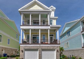 A two-story house with a front garage, a balcony on the second floor, and a small porch. - Landyn Beach House (Myrtle Beach)