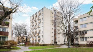 Un immeuble résidentiel à plusieurs étages, doté de balcons, d’une allée pavée et d’un espace vert.