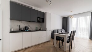 Een moderne keuken met witte kastjes, een magnetron en een eethoek met een tafel en stoelen.