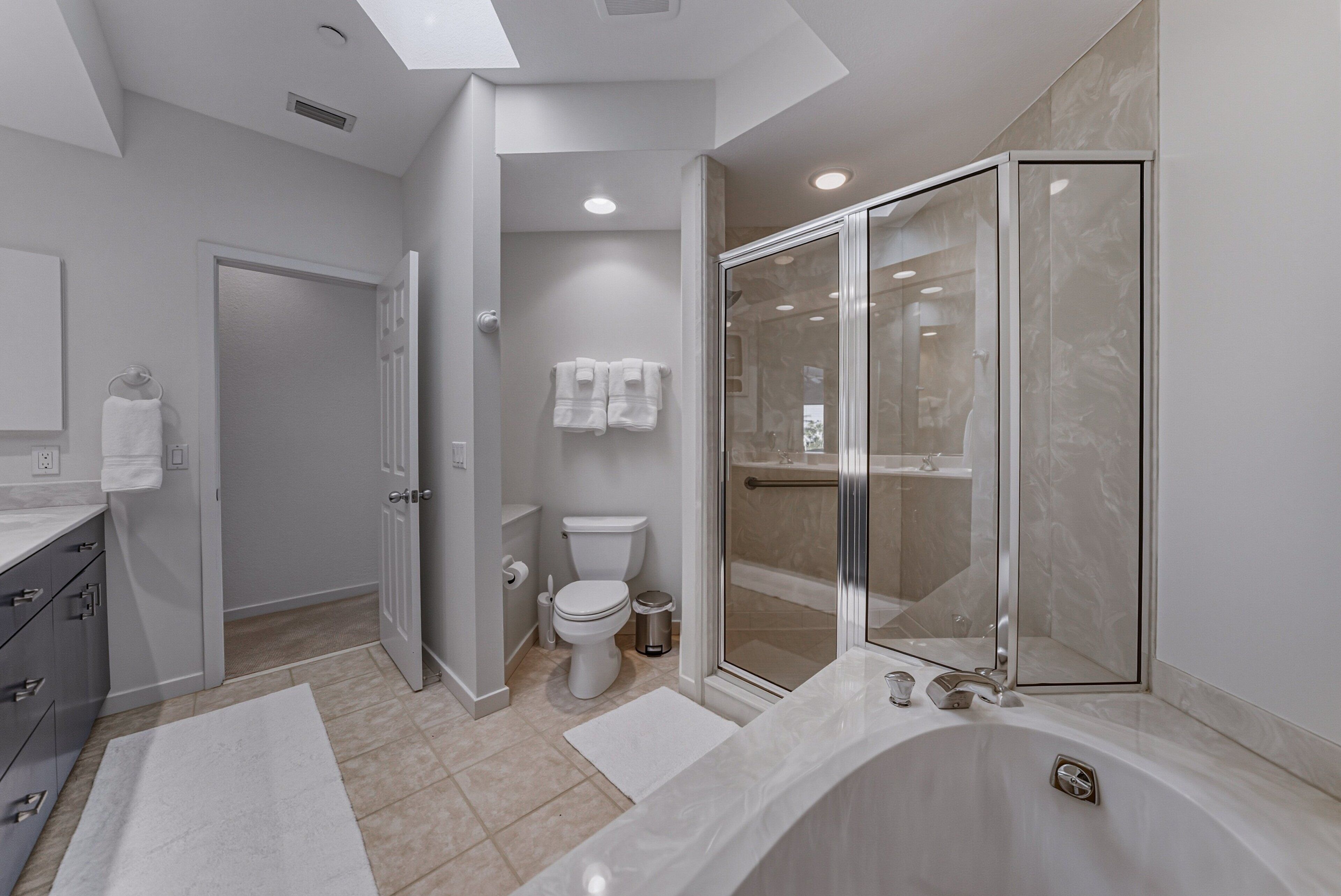 A modern bathroom with a walk-in shower, a bathtub, and a toilet.