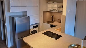 A modern kitchen with stainless steel appliances, a built-in washer, and a pendant light. - Studio Landskron Seezugang by Interhome (Ossiacher See)