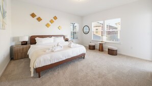 Un dormitorio con cama, mesitas de noche, lámpara y ventana con persianas.
