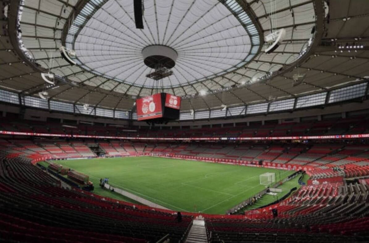 Un grande stadio con un campo centrale, gradinate a più livelli e un maxischermo.