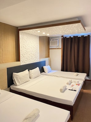 Habitación de hotel con dos camas, cabecero, aire acondicionado de pared y ventana con cortinas.