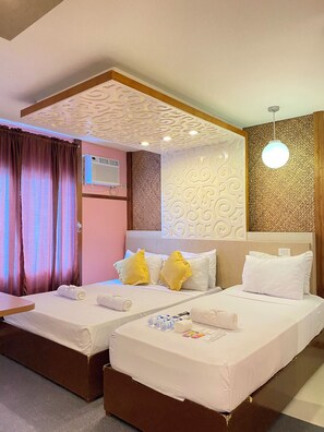 Ein Hotelzimmer mit zwei Betten, einer Decke mit dekorativen Mustern, einer Wandklimaanlage und einer Hängeleuchte.