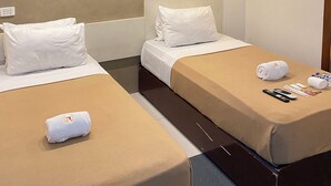 A hotel room with two single beds, a wooden headboard, a flat-screen TV, and a minibar. - Villa Rosita Hotel Naga City (Naga)