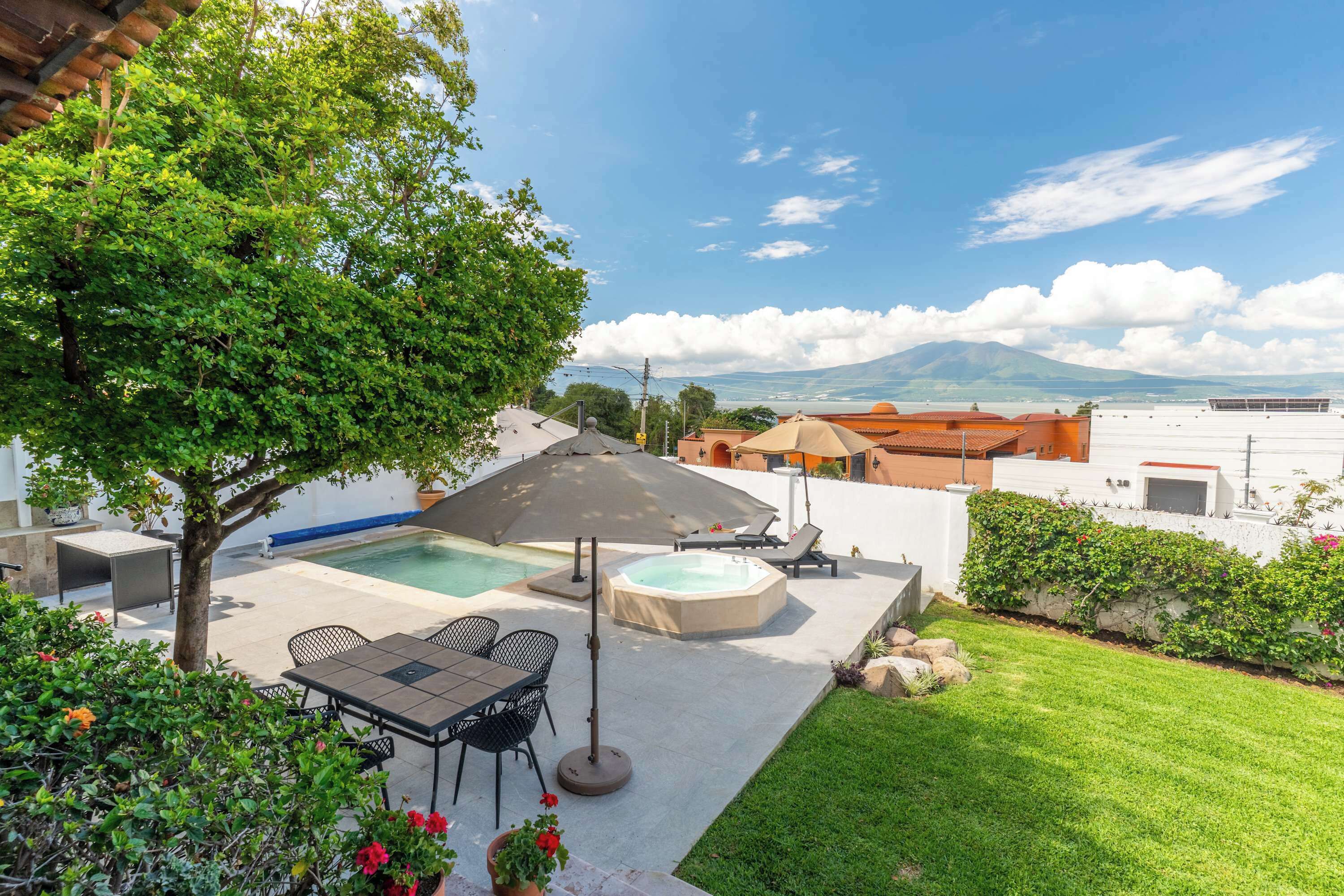 A pool with a hot tub, outdoor seating, and a view of mountains.