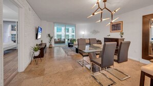 A modern dining area with a glass table, metal chairs, and a unique ceiling light fixture. - Amazing  unit/location with amenities & parking (Miami)