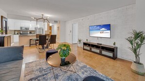 A modern living room with a flat-screen TV, a round coffee table with a plant, and a dining area with chairs and a table. - Amazing  unit/location with amenities & parking (Miami)