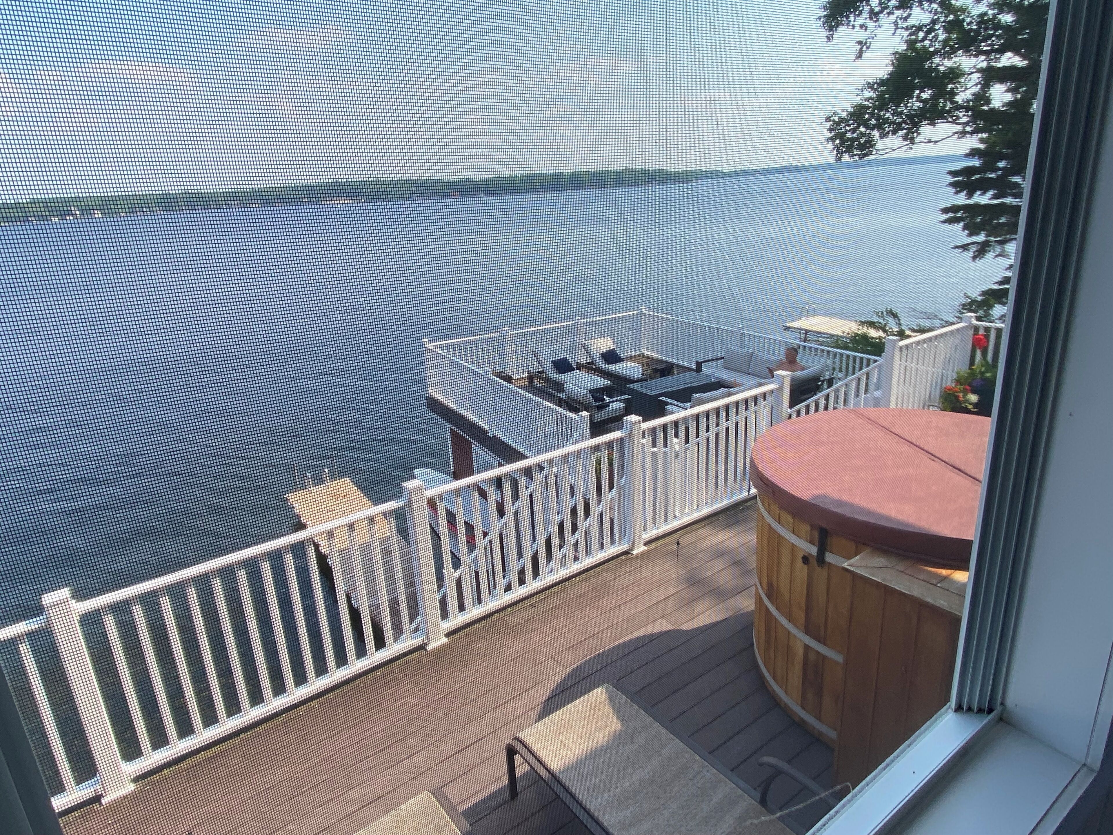 A balcony with a view of the water, a wooden deck, and a wooden barrel.
