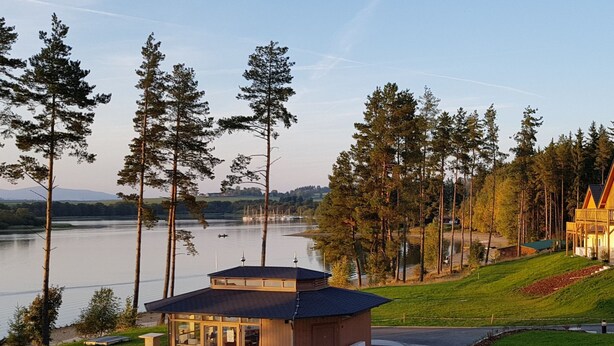 Eine am See gelegene Lodge mit Außenbereich, ein kleines Gebäude mit großen Fenstern und Blick auf den See und die umliegenden Bäume.