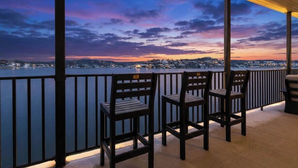 Un balcon avec des chaises donnant sur une étendue d’eau au crépuscule.