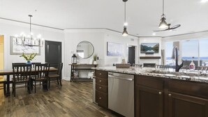 A modern kitchen with a large island, dark wood cabinetry, and a granite countertop. - Land's End #732 Gorgeous Remodel! Parking Level! (Osage Beach)
