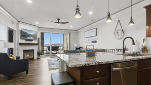 A spacious living room with a fireplace, a large TV, and a comfortable sofa. - Land's End #732 Gorgeous Remodel! Parking Level! (Osage Beach)