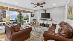 Ein modernes Wohnzimmer mit Ledersofas, einem großen Flachbildfernseher, einem Deckenventilator und einem Weihnachtsbaum.