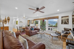 A spacious living room with a large brown leather sofa, a wooden coffee table, and a ceiling fan. - Above Par - Quiet & Private Retreat | Parking + Lake Views (Cascade)