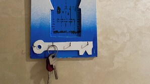 A wall-mounted key holder with a blue and white design, featuring a keyhole and a key. - Cosy seaside apartment (Tanger)