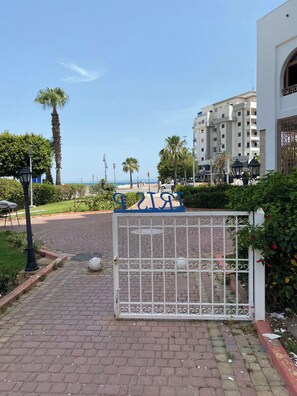 Una entrada con reja, con vista despejada a la playa y al océano de fondo.