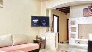 A hotel room with a large bed, a desk, a television, and a fireplace. - Cosy seaside apartment (Tanger)