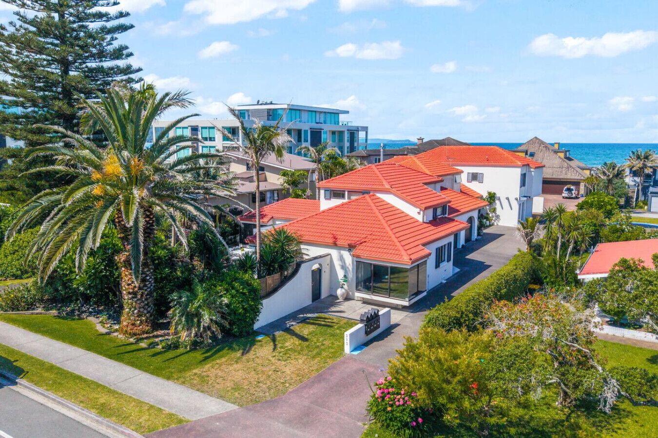 A residential area with modern houses, a clear view of the ocean, and lush greenery.