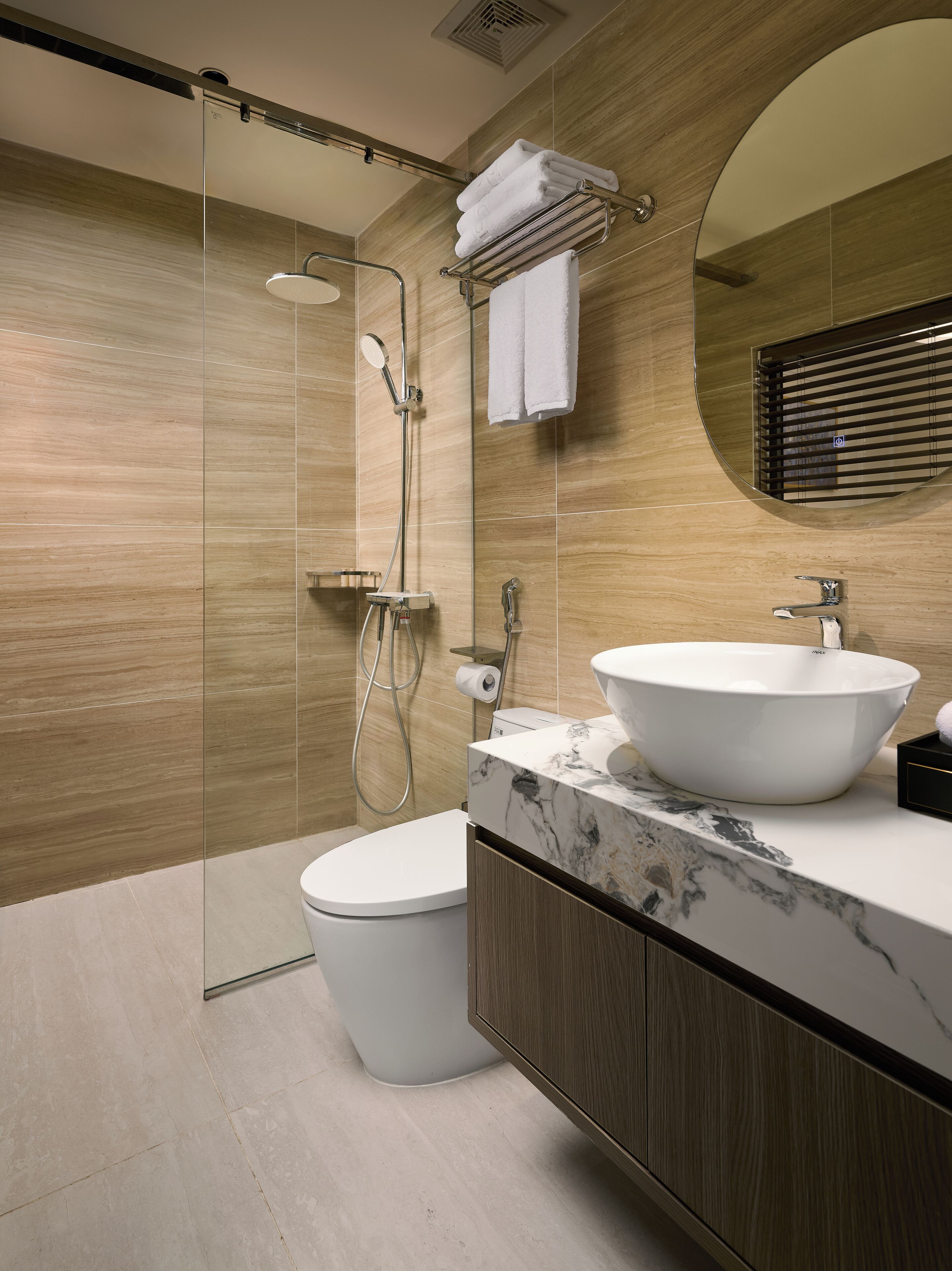 Un baño moderno con cabina de ducha de vidrio, lavamanos blanco y un inodoro.