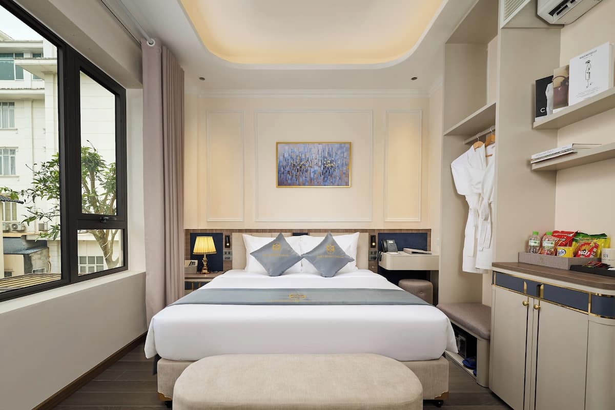 A hotel room with a large bed, bedside tables, a desk, and a wardrobe.