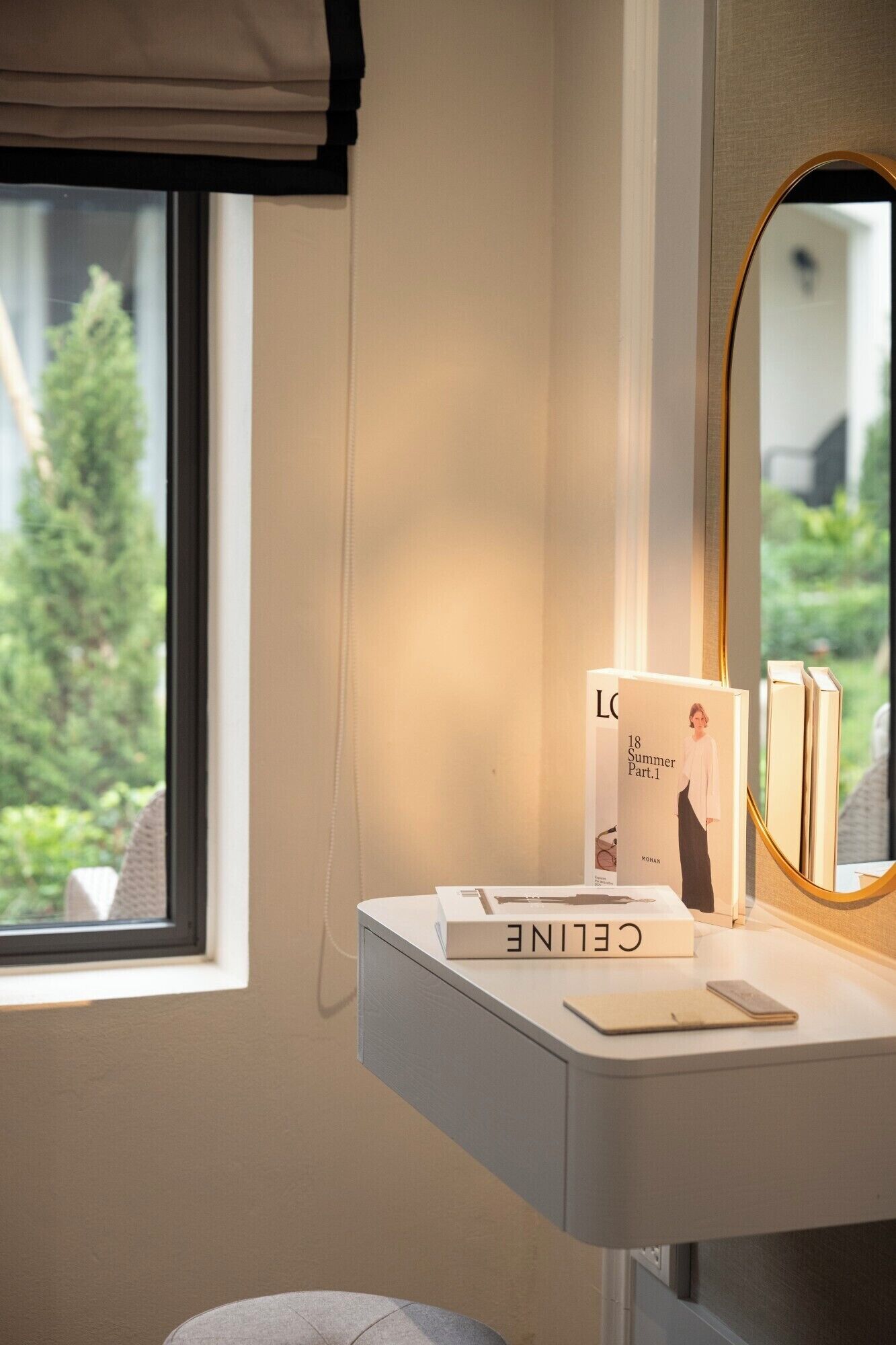 A modern bathroom with a vanity, a mirror, and a window with a view of greenery.