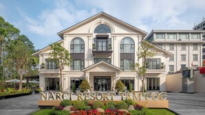 A large, two-story building with a prominent entrance and a sign reading "NARCI RESORT TAM COC".