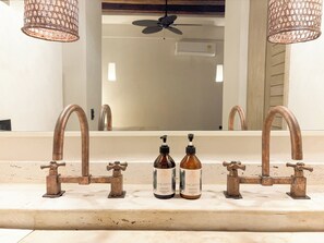 A bathroom with a large mirror, two copper faucets, and two bottles of Macarena body lotion. - Fantastic 6-bedroom villa in the heart of Cartagena de Indias (Cartagena de Indias)
