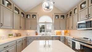 Una cocina moderna con una isla grande, electrodomésticos integrados y un amplio ventanal.