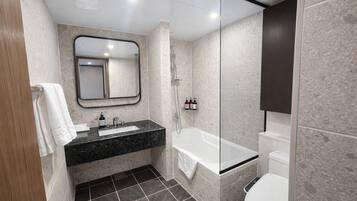 Un baño moderno con lavamanos de mármol negro, un espejo grande, una bañera y un inodoro.