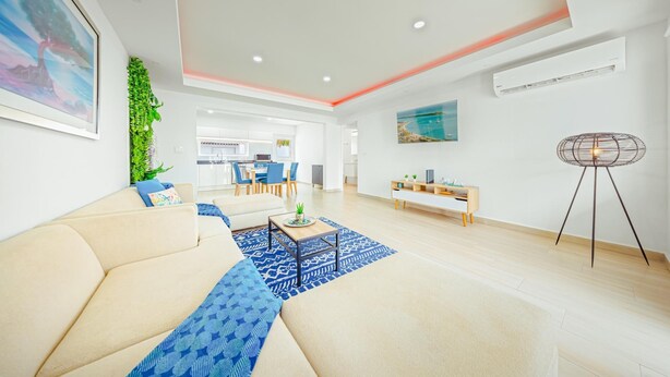 Un salón moderno con sofá, mesa de centro y comedor al fondo.