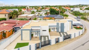 Zona residencial con casas modernas, entrada con portones y camino de acceso pavimentado.