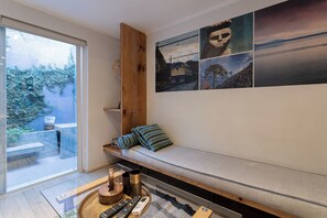 Uma sala de estar moderna com um banco embutido, uma mesa de centro de vidro e uma TV na parede.